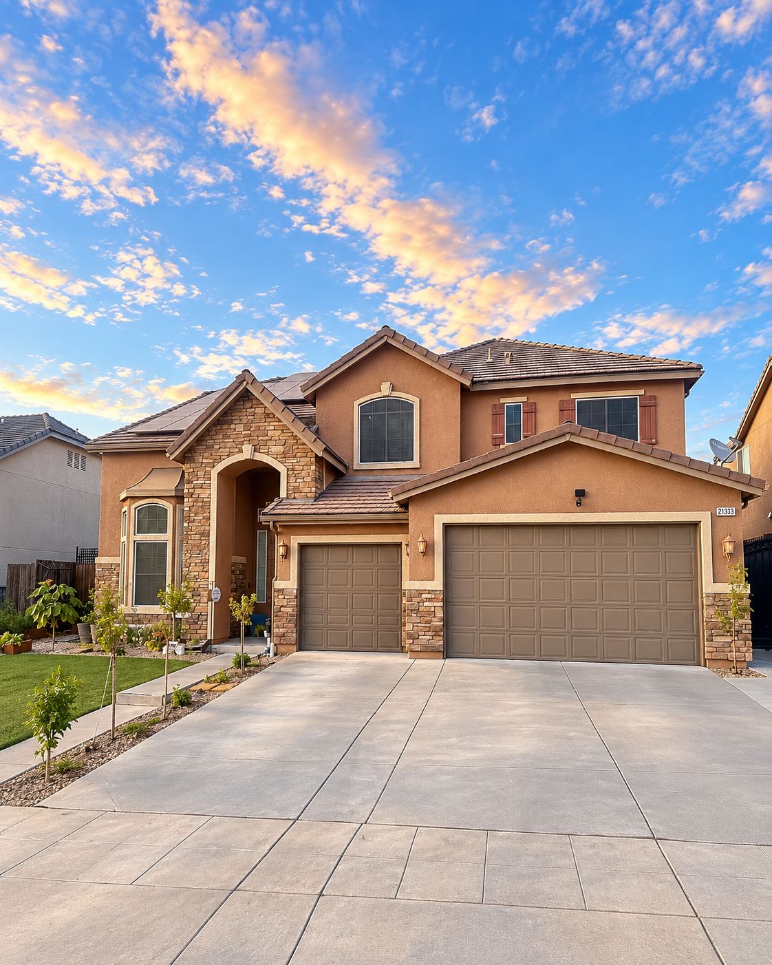 Front exterior of 21333 Tramonto Ln with stone accents and a three-car garage at sunset