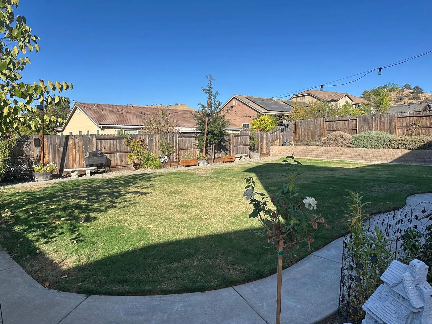 Large fenced backyard lawn with string lights